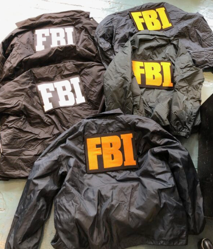 Three FBI windbreaker jackets with large FBI lettering in white, yellow, and orange — prop costumes for film and TV