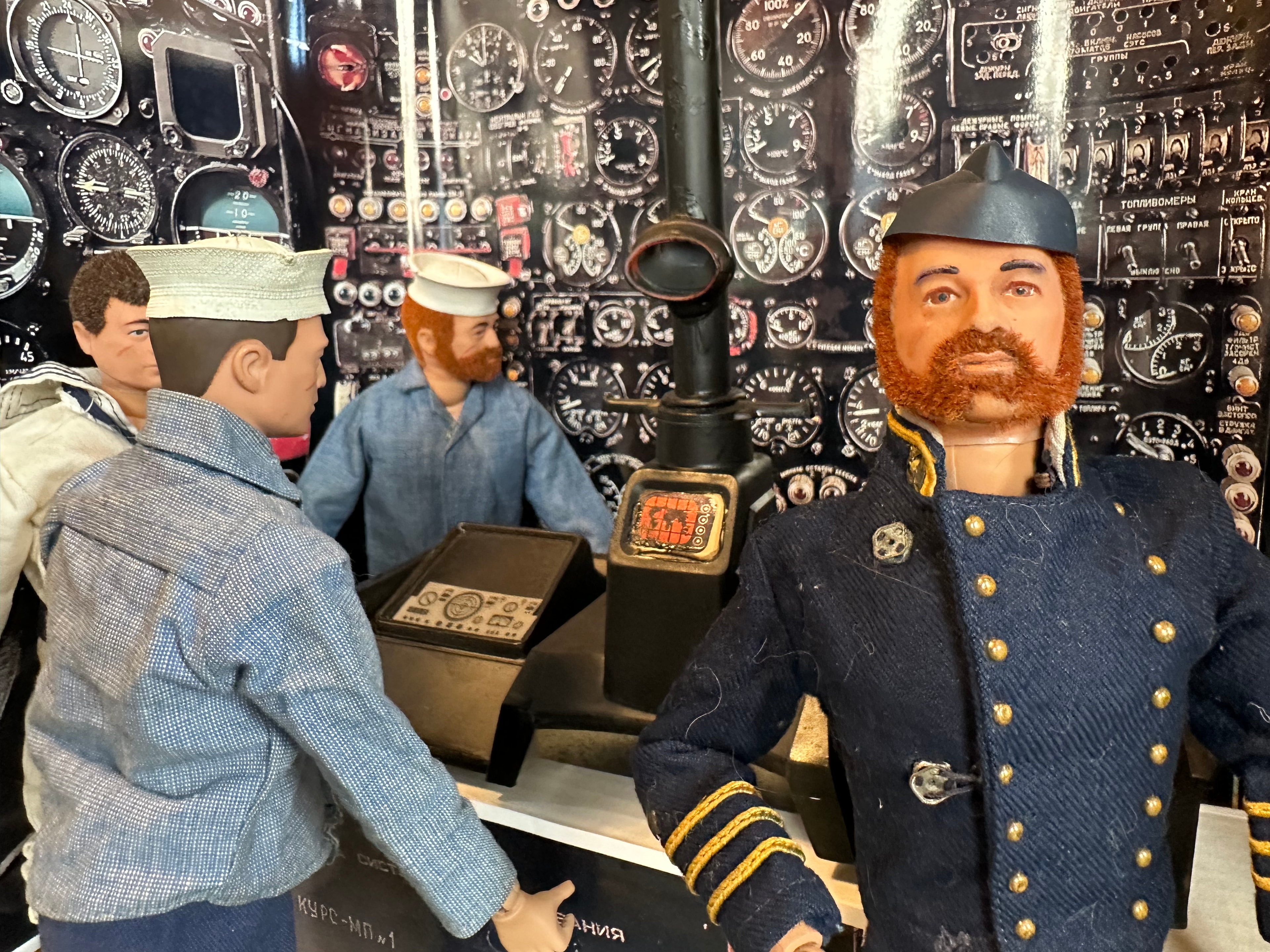 Two 1970s GI Joe figures seated in aircraft cockpit — Navy officer in dark dress uniform with gold braid and pilot in light blue flight suit
